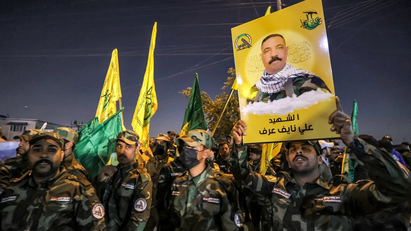 A member of Iraq's Popular Mobilisation Forces paramilitaries holds a sign identifying one of the group's slain members during a funeral procession at the PMF headquarters in Baghdad on 4 January 2024 (AFP)
