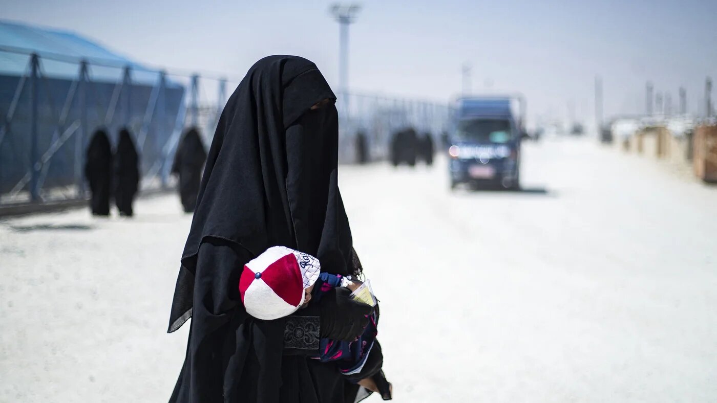 A woman carries her child at a prison camp for IS-linked detainees in northeastern Syria (AFP/Delil Souleiman)