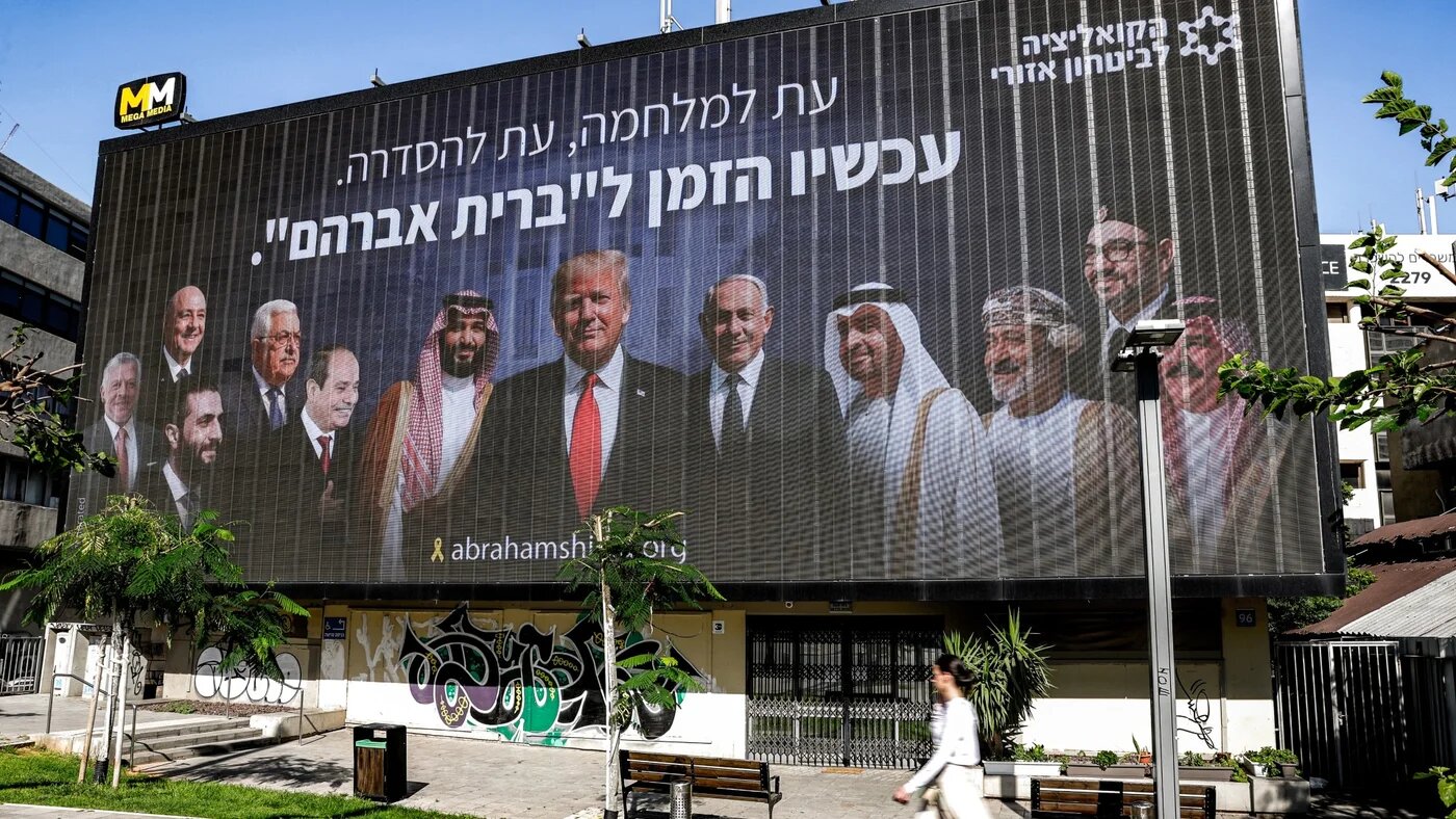 A woman walks past a billboard displayed in Tel Aviv on June 26, 2025 by the "Coalition for Regional Security" Israeli political-security initiative depicting (L to R) Jordan's King Abdullah II, Lebanon's President Joseph Aoun, Syria's interim president Ahmed al-Sharaa, Palestinian president Mahmud Abbas, Egypt's President Abdel Fattah al-Sisi, Saudi Arabia's Crown Prince Mohammed bin Salman, US President Donald Trump, Israel's Prime Ministe Benjamin Netanyahu, UAE President Sheikh Mohamed bin Zayed al-Nahy