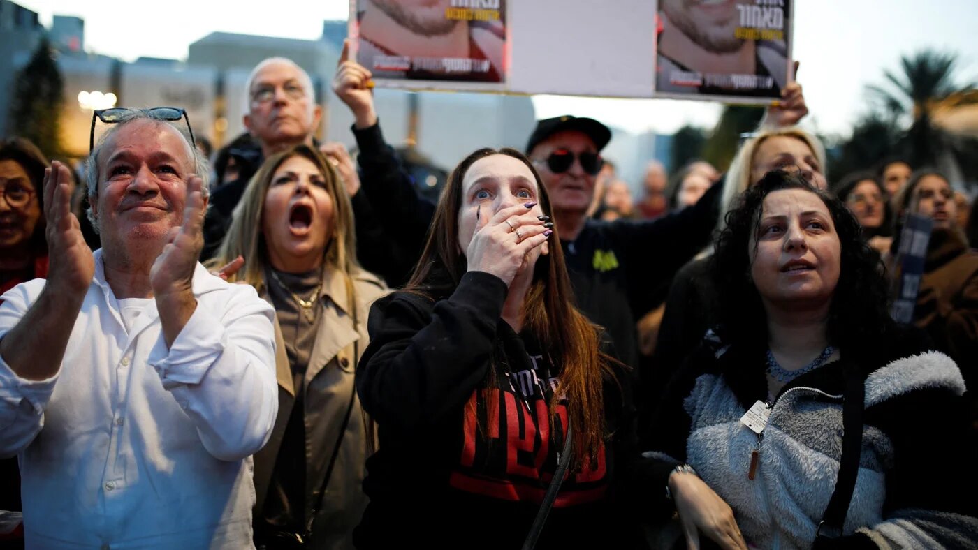 People react as they watch news coverage of the release of Romi Gonen, Doron Steinbrecher and Emily Damari in Tel Aviv, 19 January (Reuters/Shir Torem)