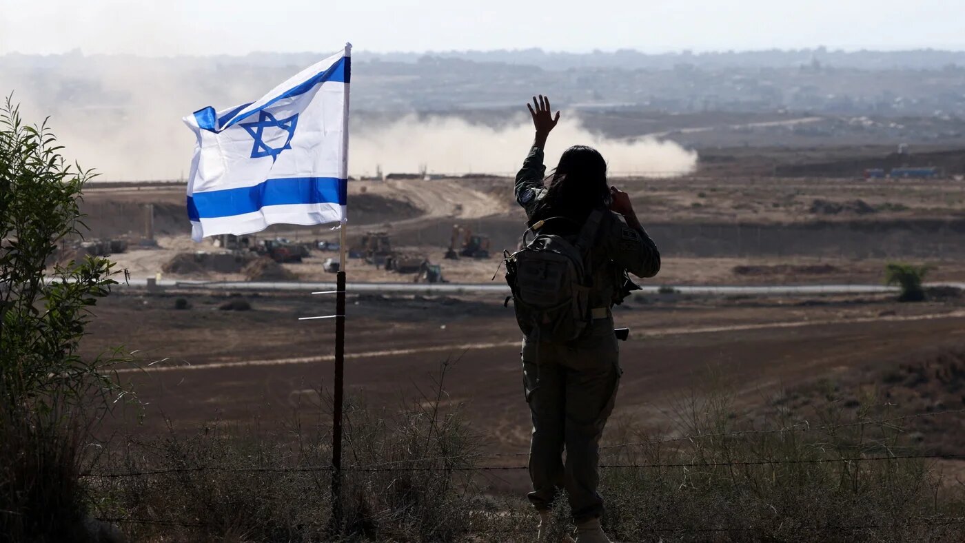An Israeli soldier gestures in the direction of Gaza from the Israeli side of the boundary, 30 July, 2025 (Reuters/Ronen Zvulun)