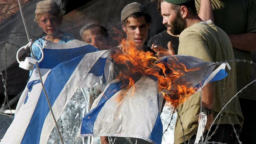 Des colons juifs et leurs partisans retranchés à l’intérieur de la colonie de Homesh en Cisjordanie brûlent un drapeau israélien, 23 août 2005, protestant contre leur évacuation par les autorités israéliennes (AFP/Thomas Coex) 