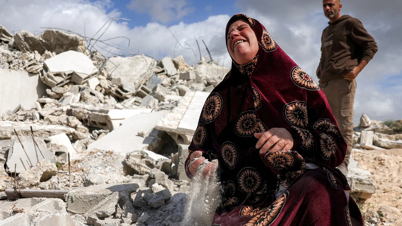 A Palestinian woman cries over rubble of her house which was demolished by Israeli forces, in the Palestinian village of Beit Awa in the, south of the occupied West Bank on 11 February, 2026 (AFP/Hazem Bader)