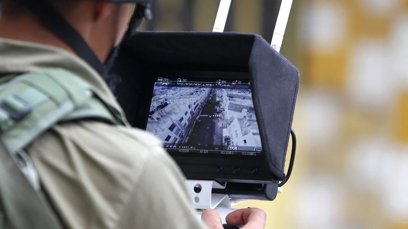 An Israeli soldier uses an unmanned surveillance drone to monitor Palestinians in the occupied West Bank city of Hebron as Israeli settlers visit the holy site of the tomb of Atnaeil Ben Kinaz on 30 September 2015.