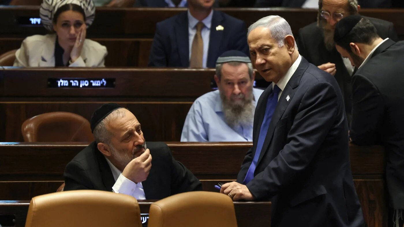 Israel's Prime Minister Benjamin Netanyahu (R) speaks with Aryeh Deri (L), chairman of the ultra-Orthodox party Shas, during a parliament session in Jerusalem on 24 July 2023 (AFP)