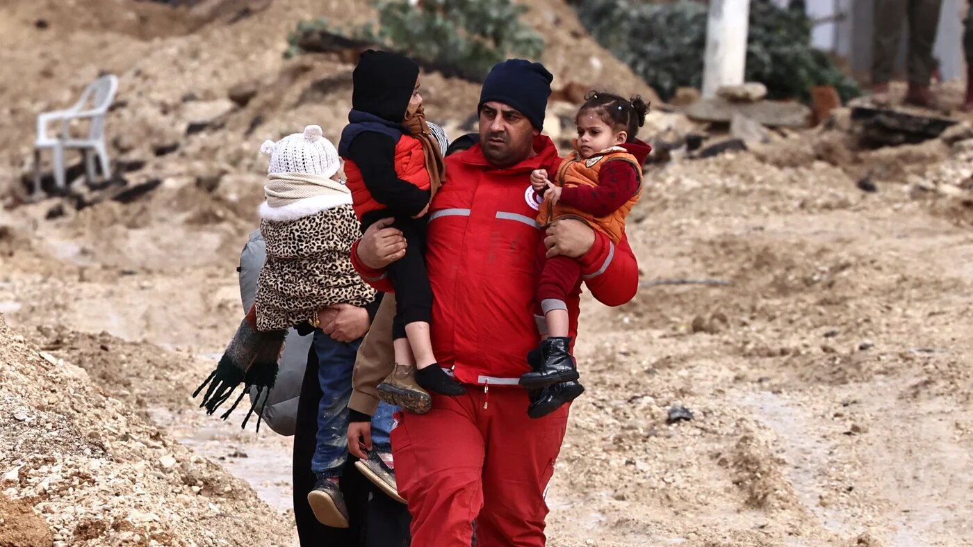 A Red Crescent member assists Palestinians leaving their homes in the Nur Shams refugee camp near Tulkarm in the occupied West Bank during an Israeli raid on 10 February 2025 (AFP/Zain Jaafar) 
