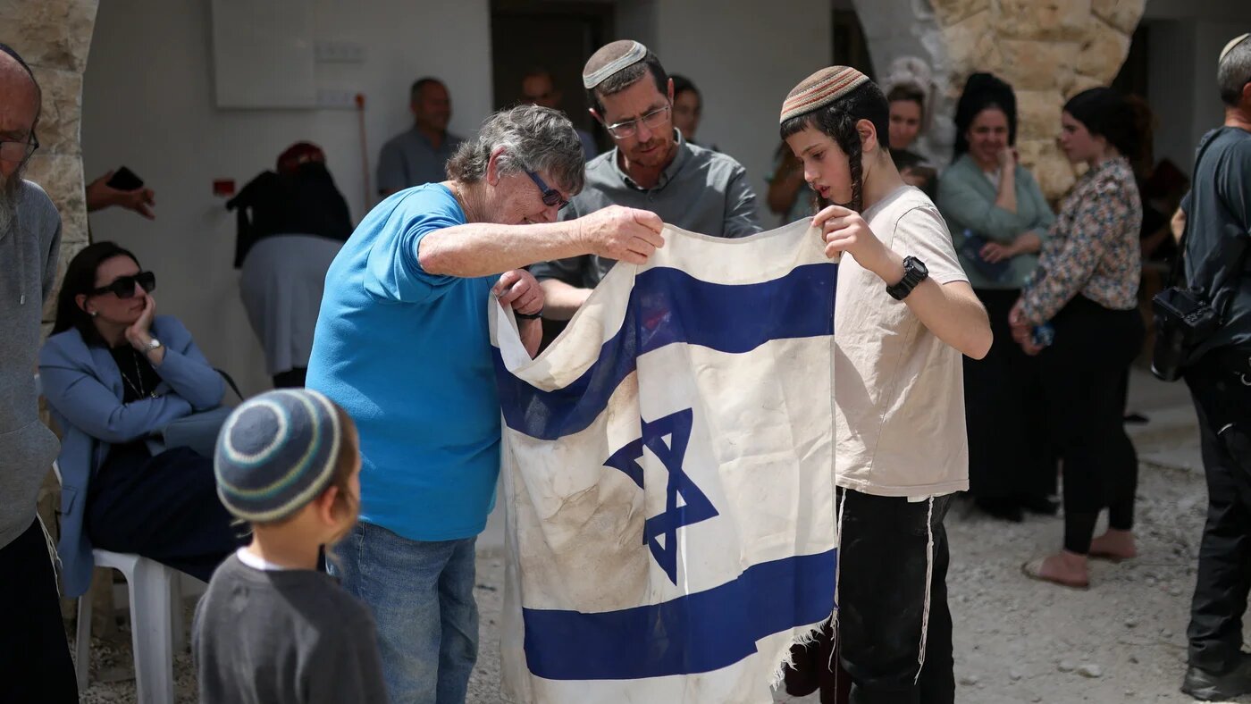 Israeli settlers hold a flag during the reestablishment of an illegal settlement in the Palestinian town of Sanur, occupied West Bank, 19 April, 2026 (Reuters/Shir Torem)