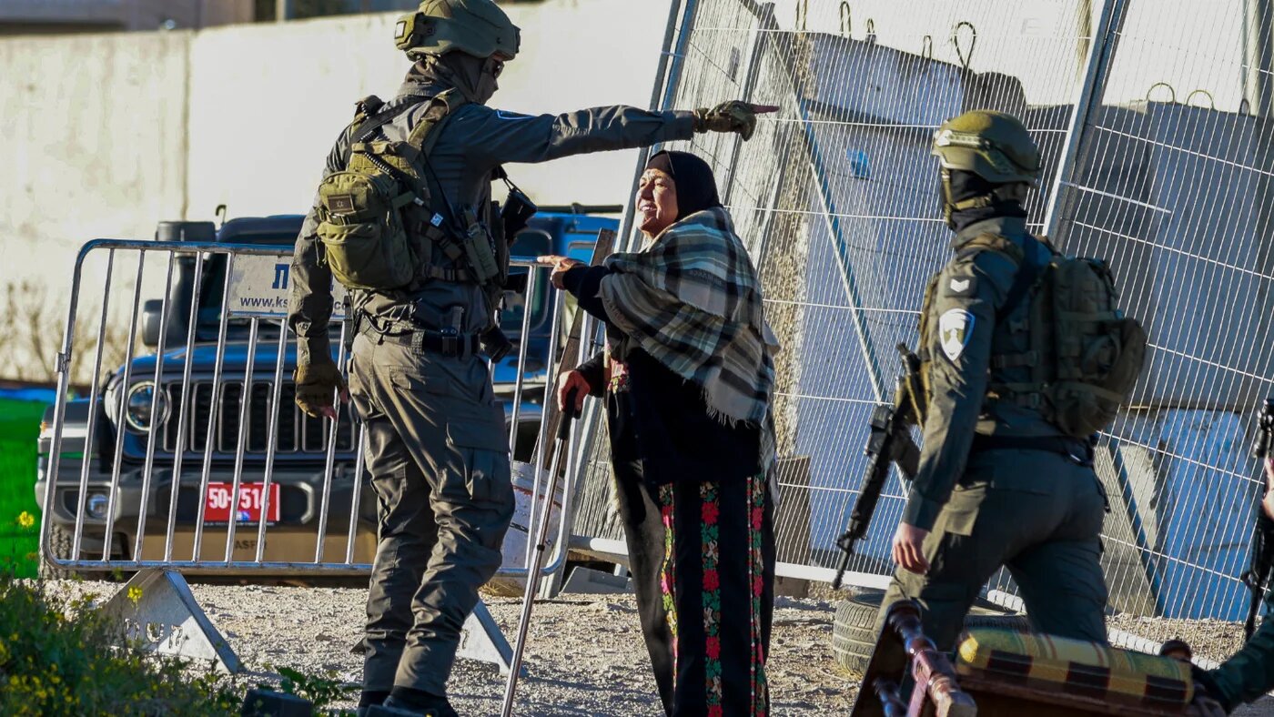 Israeli soldiers speak with a Palestinian woman at the Qalandia checkpoint in the occupied West Bank city of Ramallah on 20 February 2026 as she tries to enter Jerusalem on her way to Al-Aqsa Mosque (AFP)