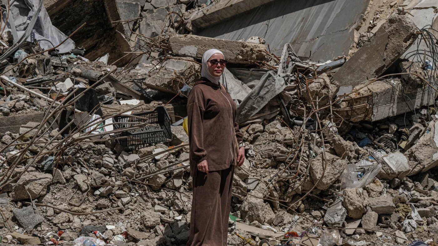 Naima poses in front of the rubble of the centre where her clinic once stood (Zaynab Mayladan/MEE)