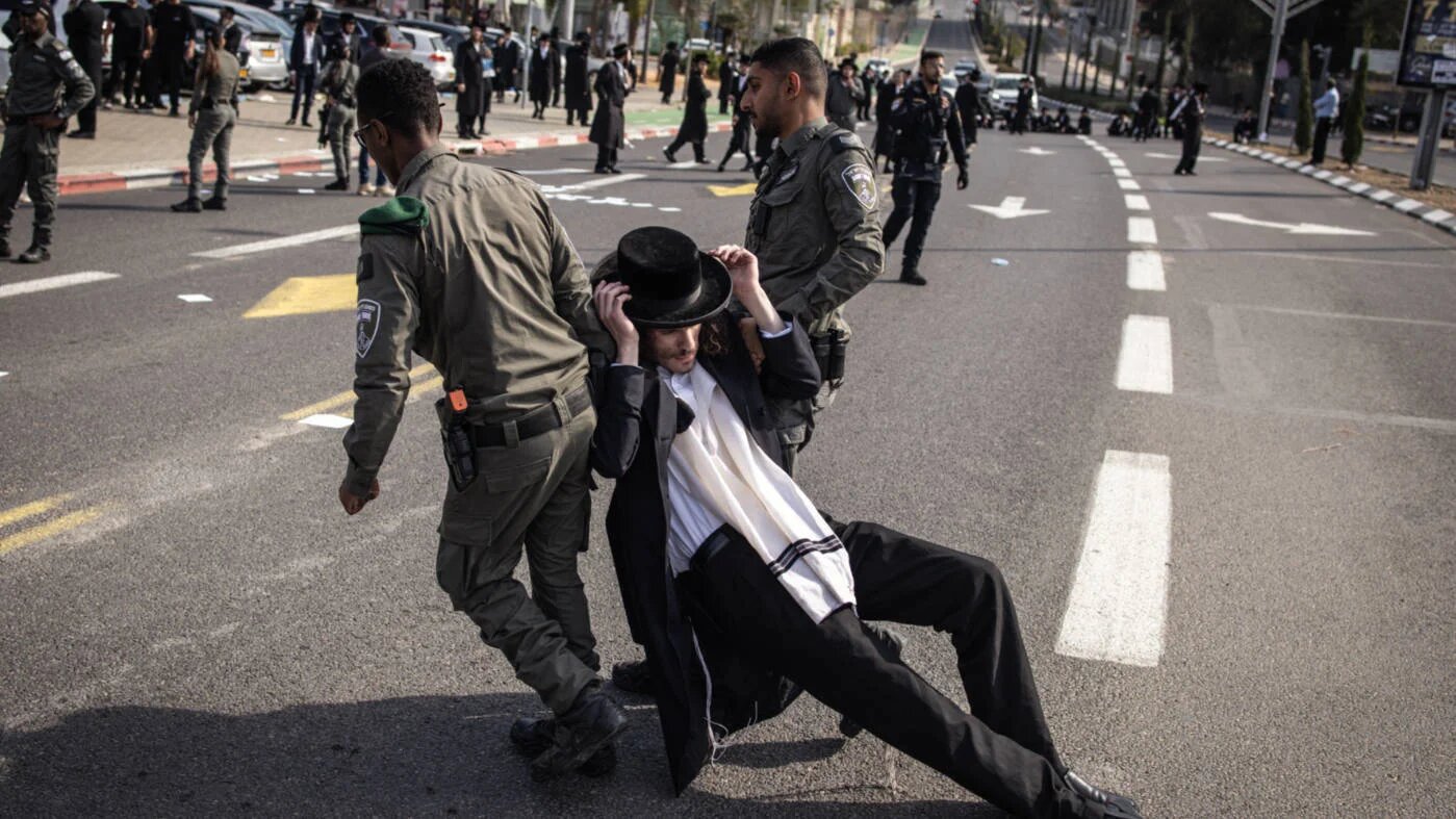 Israeli border guards disperse an ultra-Orthodox Jewish man during protest outside an army recruiting office in Kiryat Ono near Tel Aviv on 28 January  2025 (AFP)