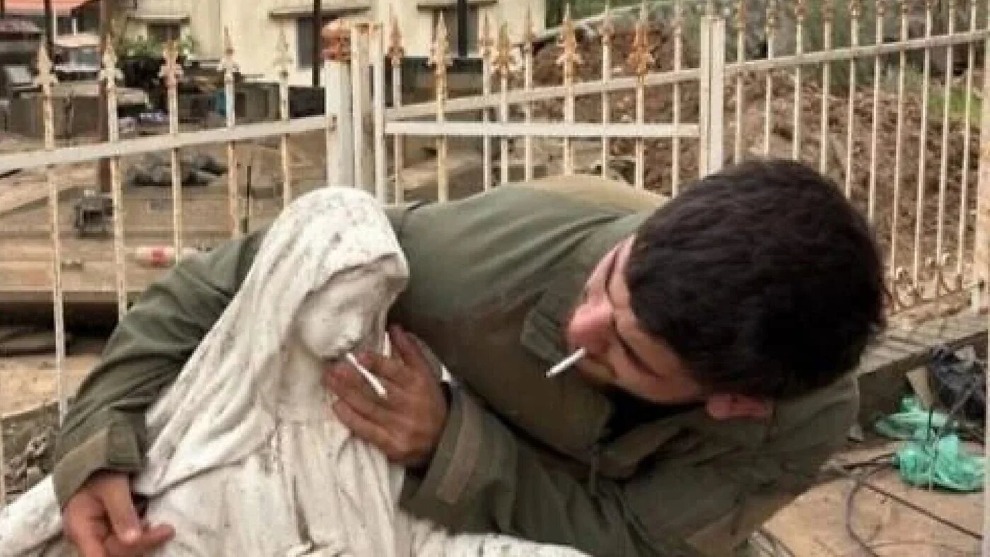 An soldier was pictured placing a cigarette into the mouth of a Virgin Mary statue in the Christian village of Debel (X/Screengrab)