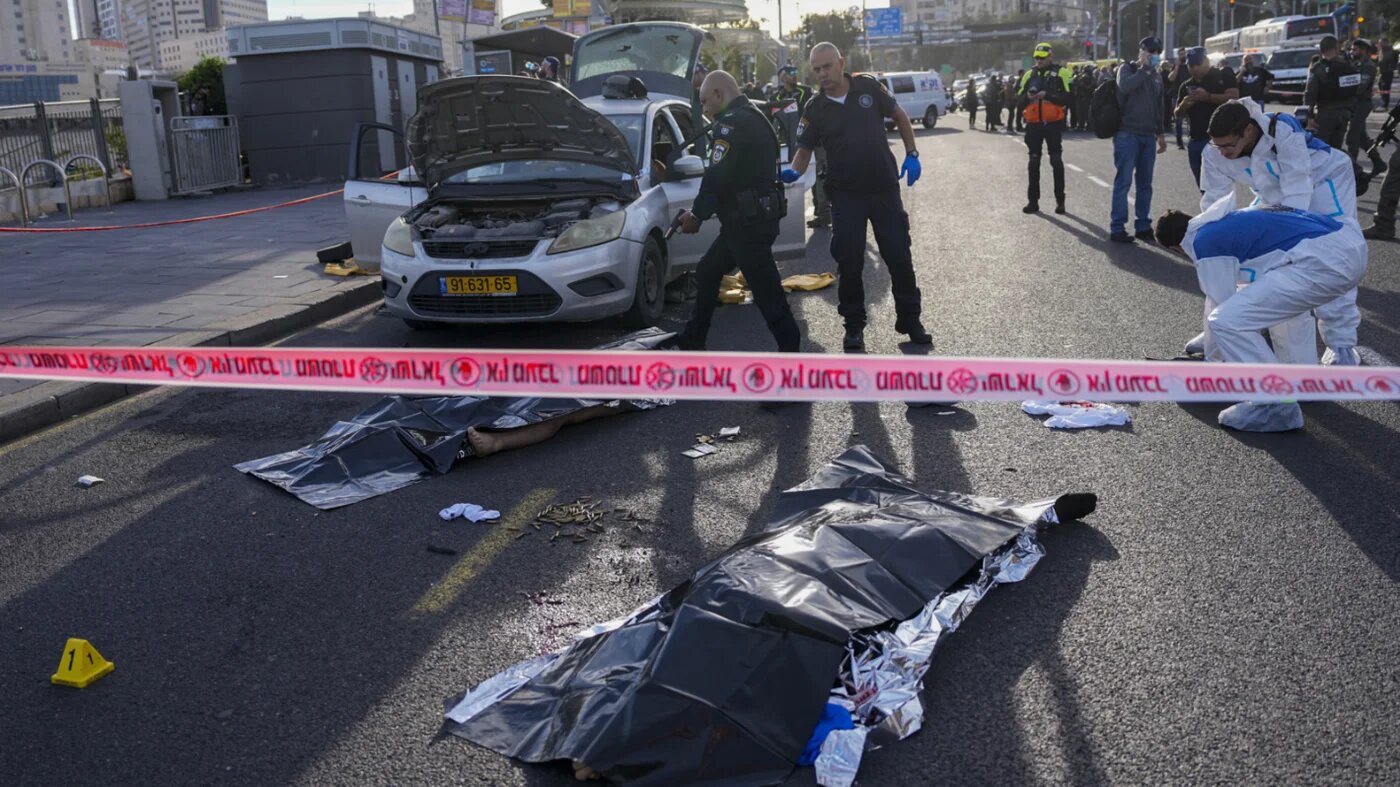 Israeli police officer pointing his gun at killed Palestinian attacker