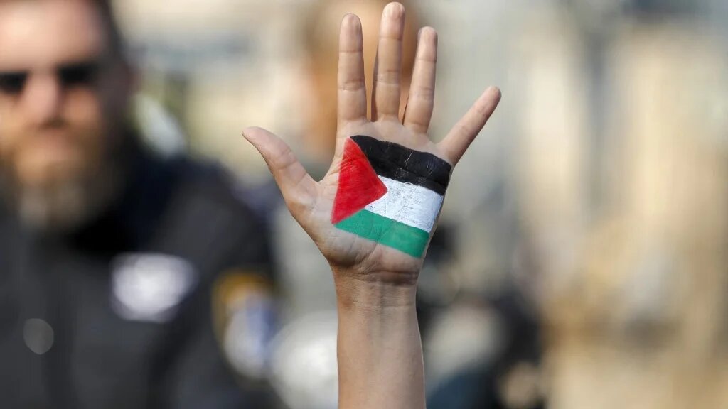 A demonstrator raises her hand, painted with the colours of the Palestinian flag, during a protest in Jerusalem on 30 July 2021 (AFP)
