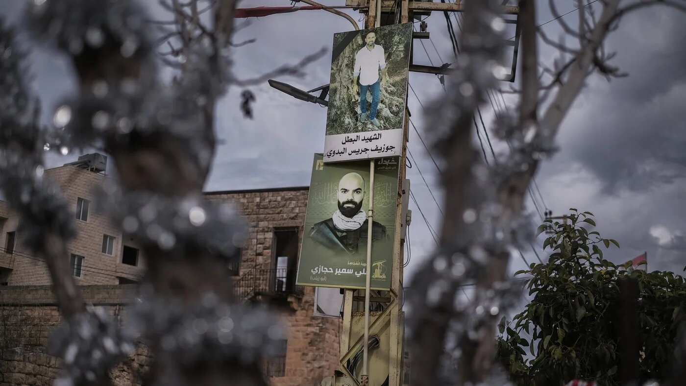 Posters showing Hezbollah members and civilians killed by Israel in south Lebanon are seen behind a tinsel-covered tree in Derdghaya, 21 December (João Sousa/MEE)