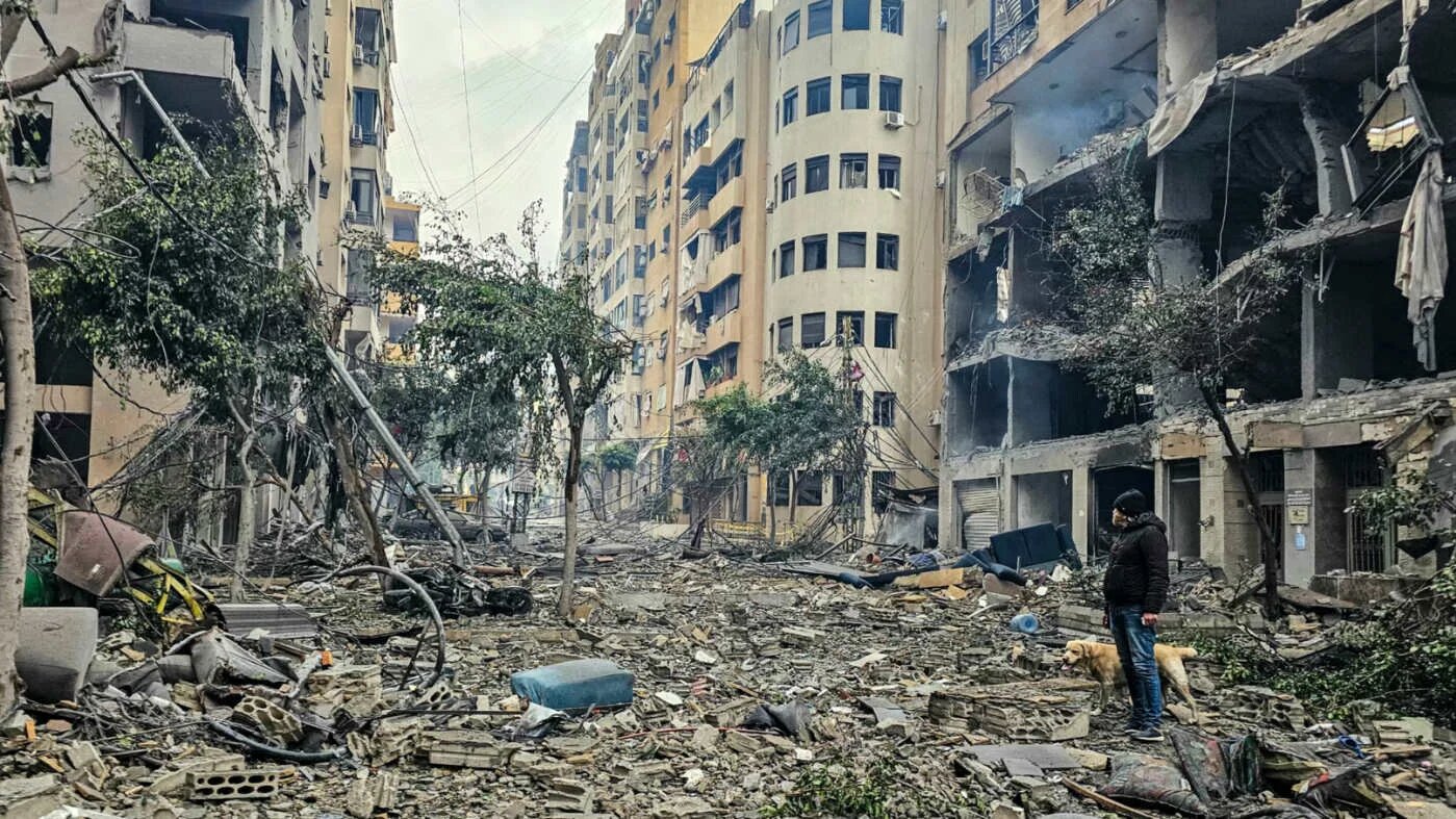 A man and his dog walk across the rubble of a building at the site of an Israeli airstrike in Beirut’s southern suburb of Haret Hreik on 15 March 2026 (AFP)