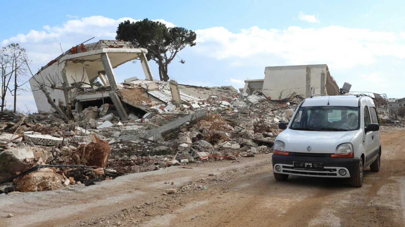 Residents drive past a damaged site as they return to the Lebanese village of al-Khiam, near the border with Israel, on 23 January 2025 (Karamallah Daher/Reuters)