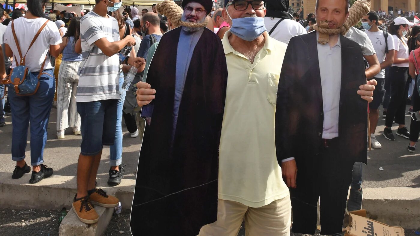 A man holds a cut-out of Hezbollah leader Hassan Nasrallah (L) and former Foreign Minister Gebran Bassil.