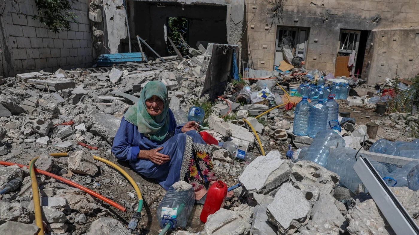 Khadija Amara, whom local residents said had not left her home, fills a jerrycan with water as she sits among the rubble of a house, which was damaged by an Israeli strike, in Qlaileh in the Tyre district, southern Lebanon, June 19, 2026. REUTERS/Zohra Bensemra TPX IMAGES OF THE DAY