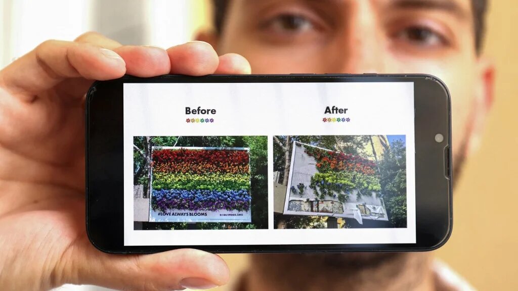 Hadi Damien, l’initiateur de Beirut Pride, montre des photos d’un panneau d’affichage avec des fleurs aux couleurs d’un drapeau arc-en-ciel, avant et après sa destruction, à Beyrouth, le 1er juillet 2022 (AFP/Anwar Amro)