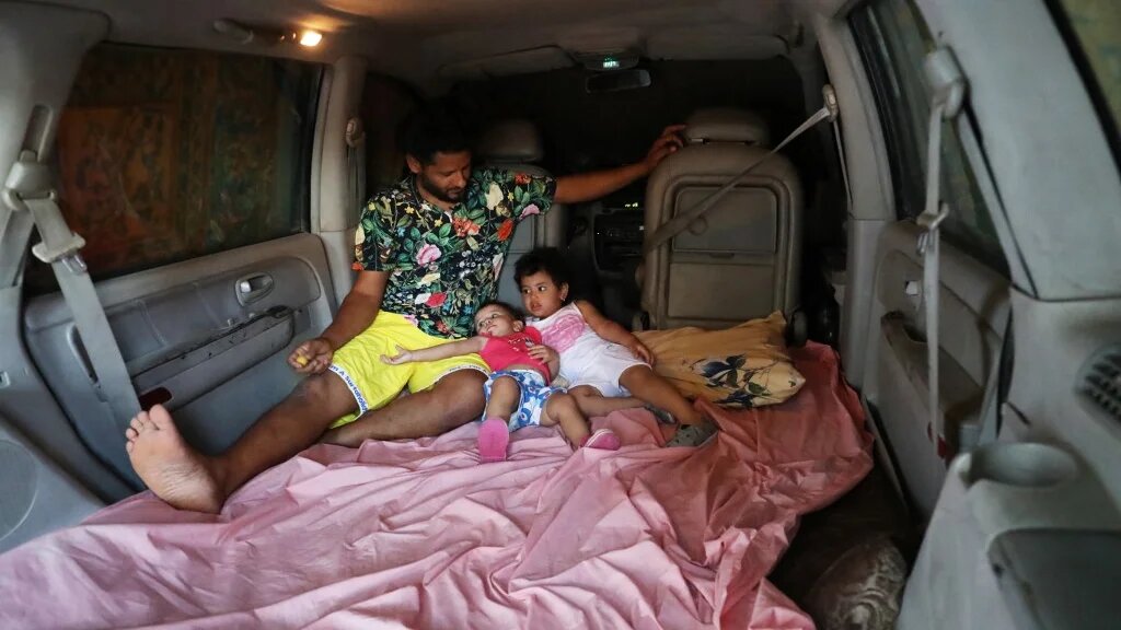 Mahmoud Aguil dort en famille dans sa voiture pour profiter de la climatisation (AFP/Mahmud Turkia)