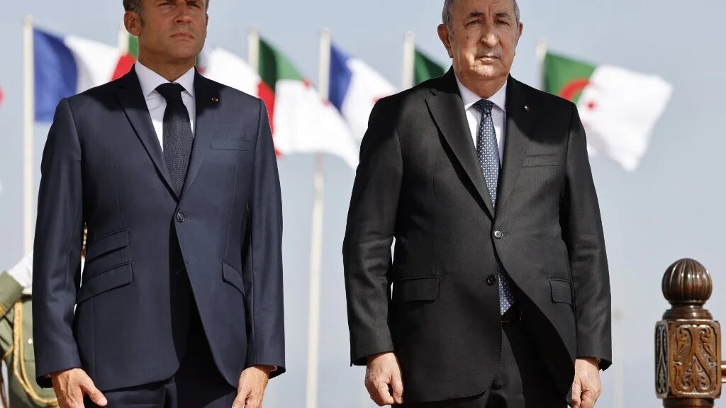 Emmanuel Macron et Abdelmadjid Tebboune écoutent les hymnes nationaux de leurs pays, à l’aéroport d’Alger le 27 août 2022 (AFP/Ludovic Marin)