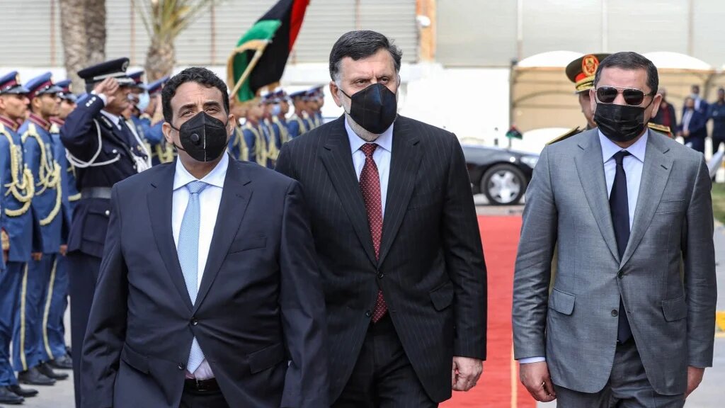 Le chef du conseil présidentiel libyen Mohamed al-Manfi (à gauche) et le Premier ministre Abdel Hamid Dbeibah (à droite) arrive avec le dirigeant du GNA Fayez al-Sarraj pour le transfert de pouvoir à Tripoli, le 16 mars (AFP)