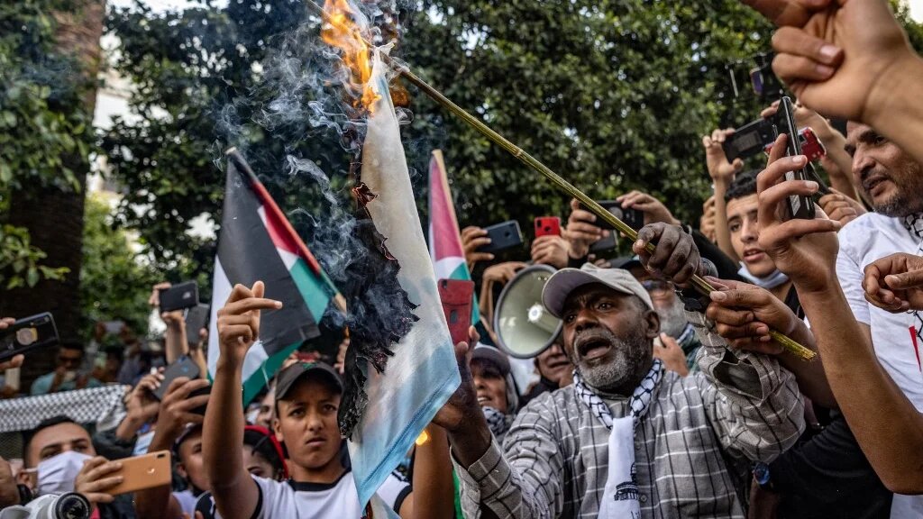 Des Marocains brûlent le drapeau israélien lors d’une manifestation contre la normalisation à Rabat, le 16 mai 2021 (AFP/Fadel Senna)