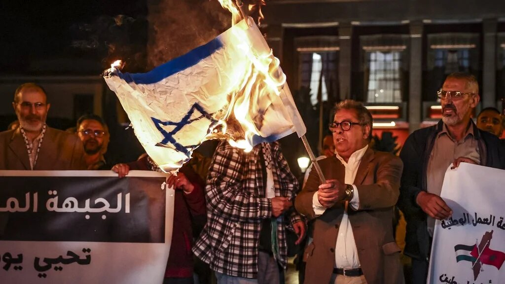 Pendant une manifestation en soutien à la Palestine devant le Parlement de Rabat, un Marocain brandit un drapeau israélien en feu (AFP/Fadel Senna)