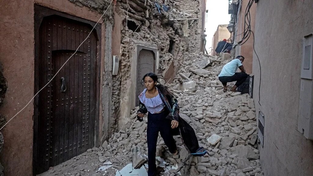 Une femme évacue sa maison avec ses affaires à travers les décombres dans la vieille ville de Marrakech, le 9 septembre 2023 (AFP/Fadel Senna)
