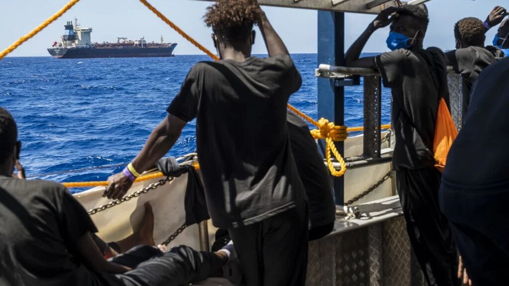 Migrants onboard a civil sea rescue ship watch towards the oil tanker Maersk Etienne off the coast of Malta on 27 August 2020.