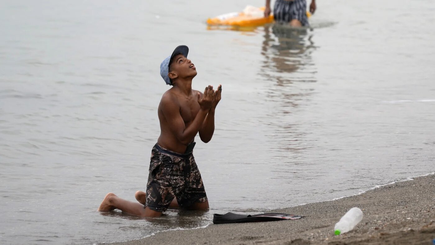 A boy gestures on the beach around the border barrier with Morocco to enter Spain's north Africa's Ceuta enclave on 31 July 2026 (AFP)
