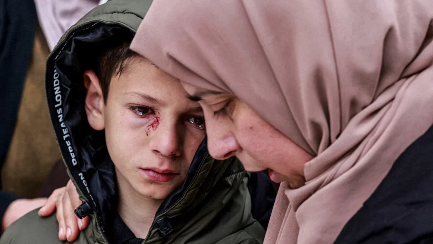 Mustafa Odeh, who was wounded but survived after Israeli soldiers fired on the car carrying his parents and three siblings, is comforted during the funeral of his family in the northern West Bank town of Tammun on 15 March 2026 (Jaafar Ashtiyeh/AFP)