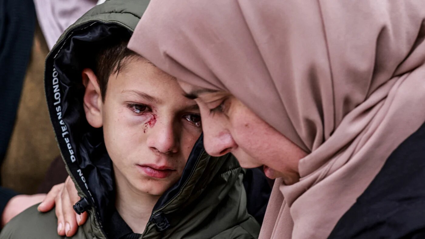 Mustafa, who was wounded but survived after Israeli soldiers fired on the car carrying his parents and three siblings, is comforted during the funeral of his family in the northern West Bank town of Tammun on 15 March 2026 (AFP)