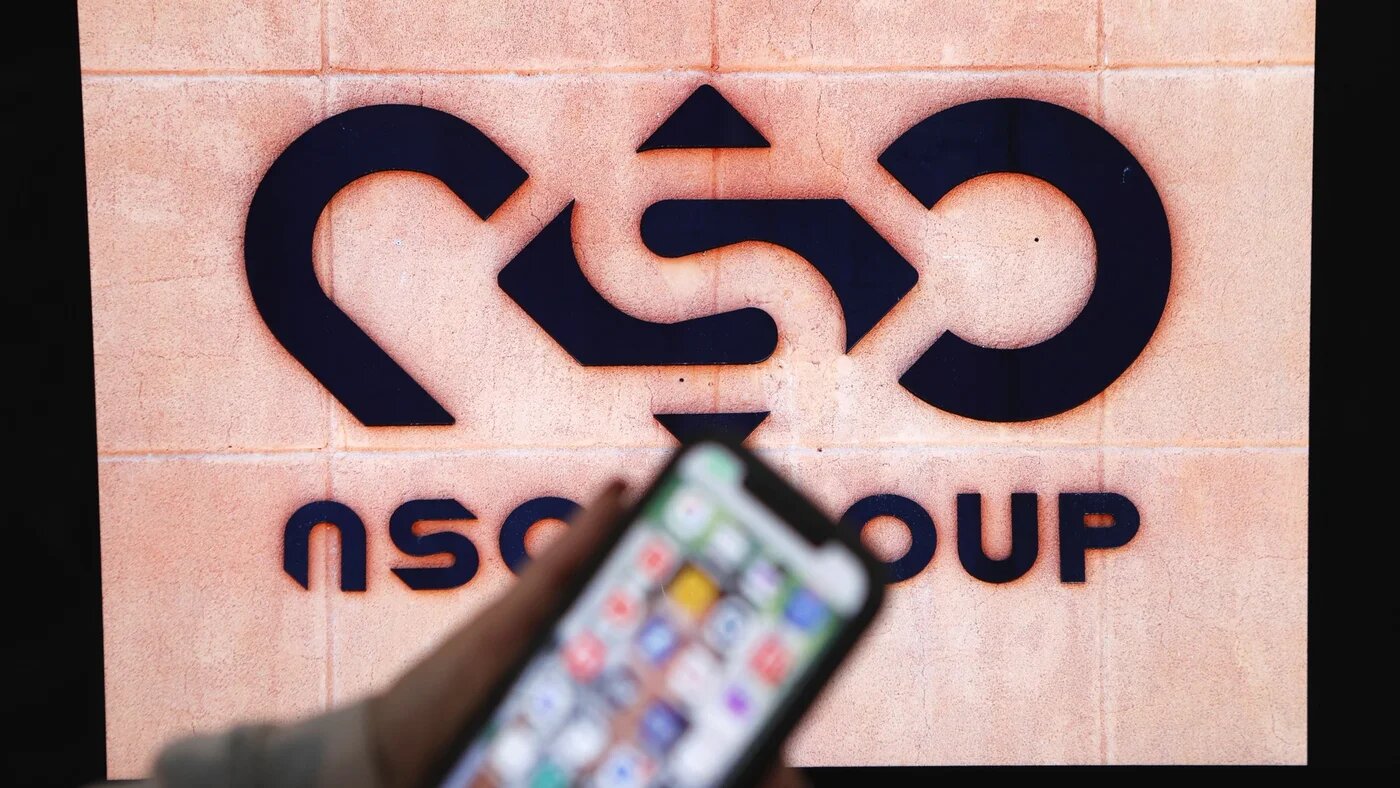 A photographic illustration shows a mobile phone near the NSO Group company logo on 9 February 2022 in the Israeli city of Netanya (AFP/Jack Guez)