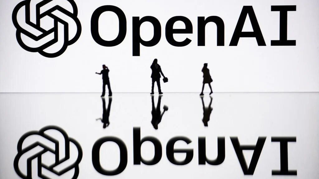 This illustration photograph, taken in October 2023 in Mulhouse, France, shows figurines next to a screen displaying a logo of the US firm OpenAI (Sebastien Bozon/AFP)