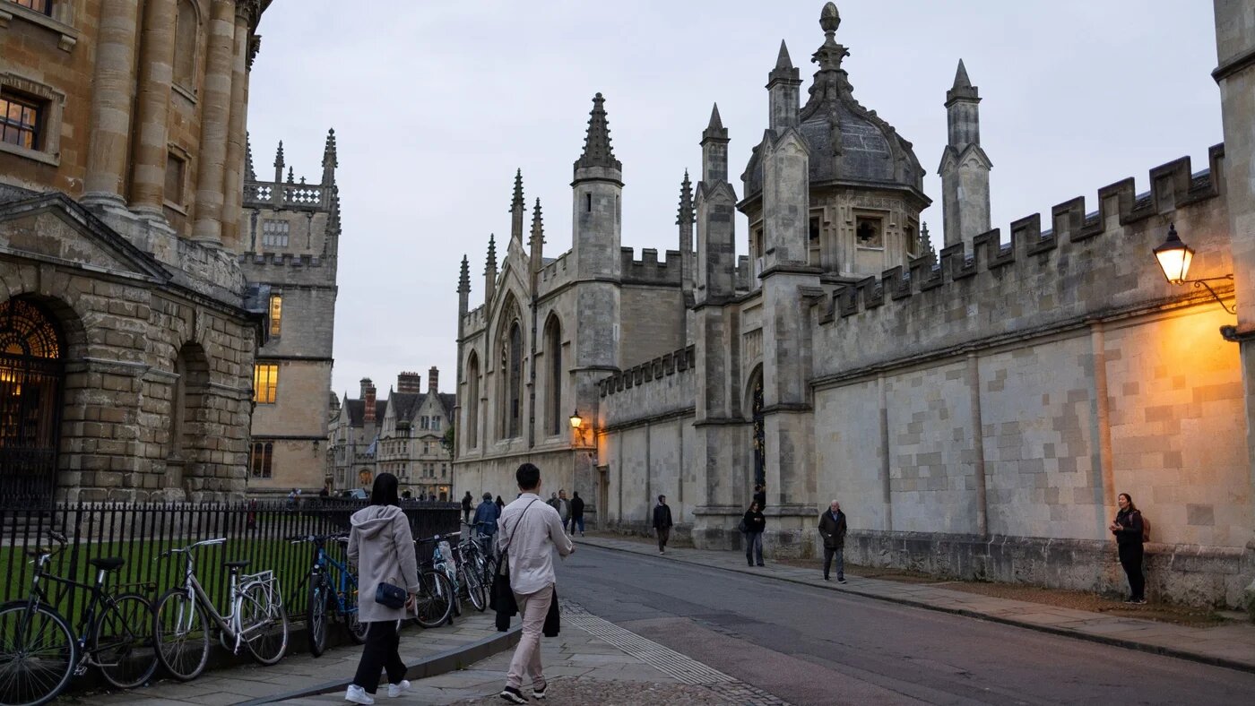People walk outside the College of All Souls, in Oxford, on 20 October 2023 (AFP/Henry Nicholls)