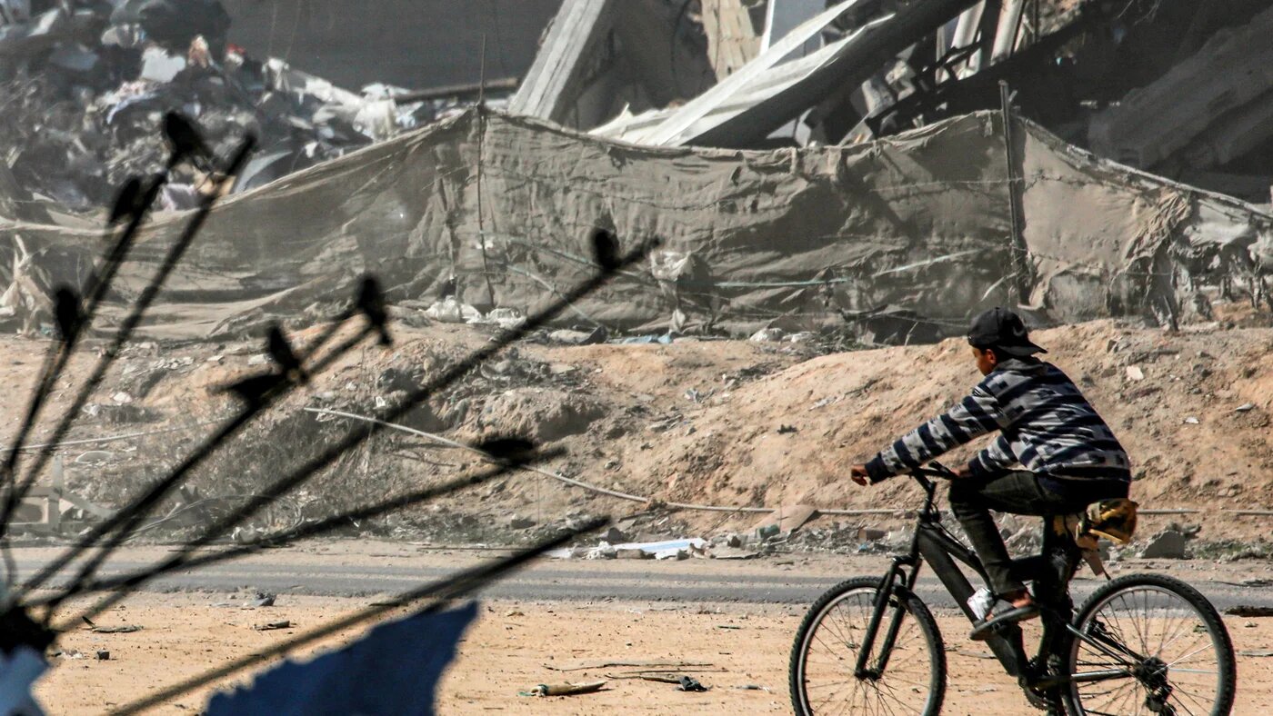A boy rides his bicycle past destroyed infrastructure east of Rafah in the southern Gaza Strip on 21 January 2025 (Bashar Taleb/AFP)