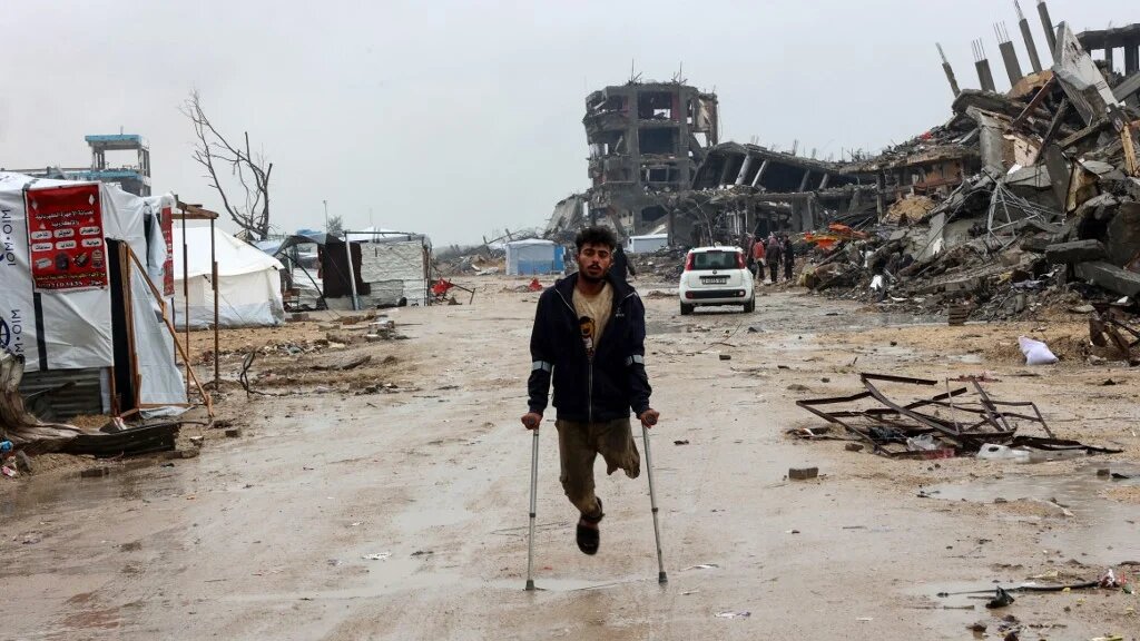 A Palestinian amputee walks near destroyed buildings in Beit Hanoun, in the northern Gaza Strip, on 12 February 2025 (Omar al-Qattaa/AFP)