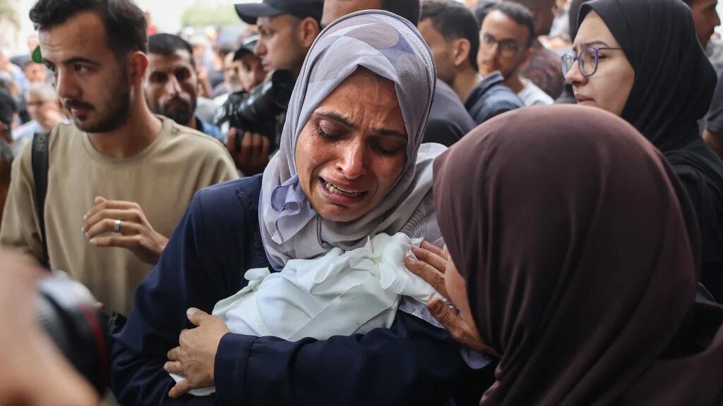 A Palestinian woman cries as she carries the body of a baby killed in Israeli strikes on Gaza City, before a funeral procession outside al-Shifa hospital, on 4 September 2025 (Omar al-Qattaa/AFP)