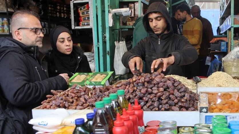 A vendor serves dates to a customer in Gaza City on 1 March 2025 (Omar al-Qattaa/AFP)