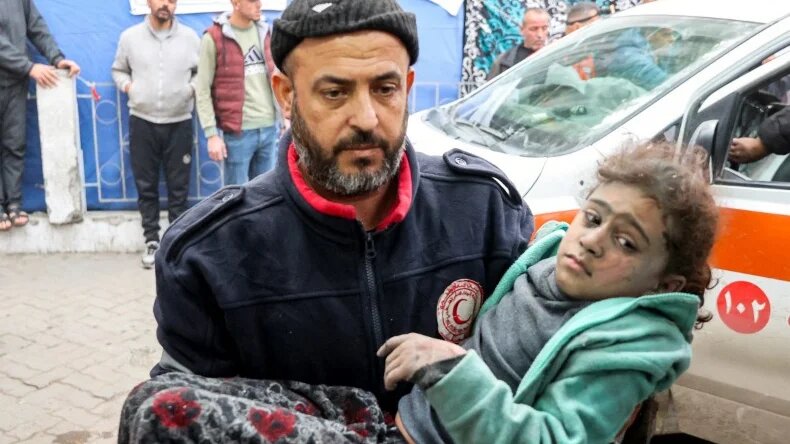 A man carries a girl rescued from the rubble of a collapsed building to receive medical care at al-Ahli hospital in Gaza City, on 4 January 2025 (Omar al-Qattaa/AFP)