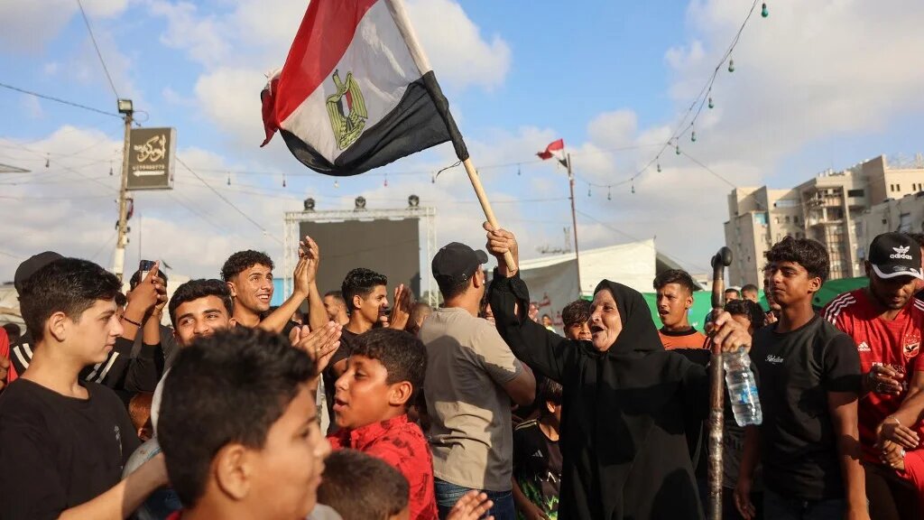 A woman waves an Egyptian flag as Palestinians watch the World Cup match between Egypt and Argentina on a giant screen in Gaza City, on 7 July 2026 (Omar al-Qattaa/AFP)