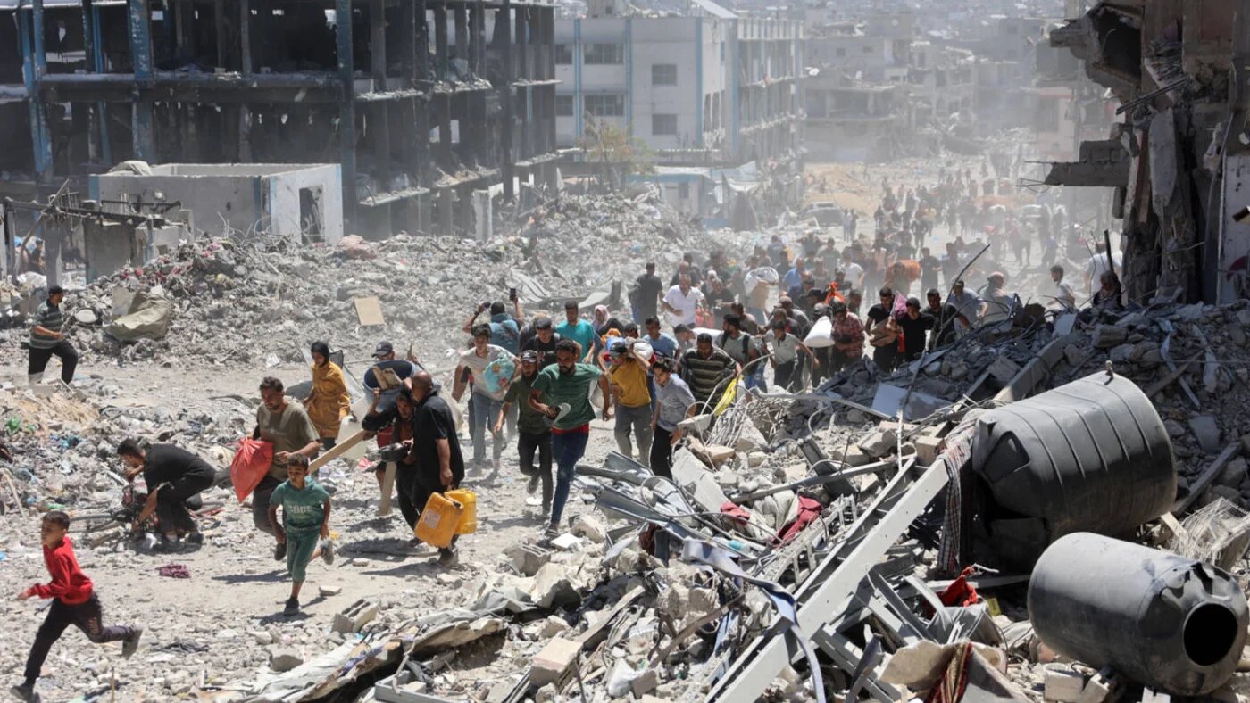 Palestinians who returned briefly to the Jabalia refugee camp in the northern Gaza Strip run for cover after a school was hit by an Israeli strike on 30 May 2024 (AFP)