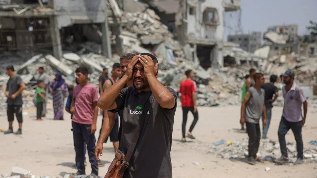 A man reacts as medics transport victims of reported Israeli strikes on members of Palestinian aid security committees in northern Gaza on 13 August 2025 (Bashar Taleb/AFP)