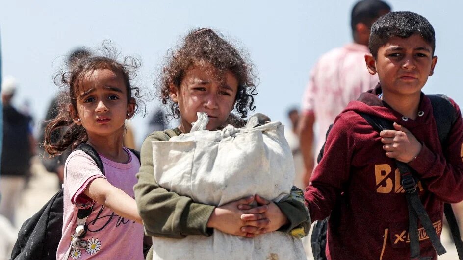 Displaced Palestinians carry their belongings in Nuseirat, Gaza, on 14 April 2024 (AFP)