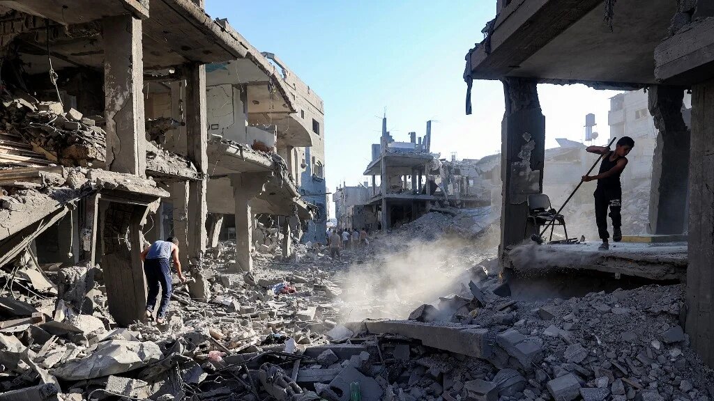A boy sweeps through the rubble of a building destroyed in an Israeli bombardment of Maghazi refugee camp, in the central Gaza Strip, on 12 June 2026 (Eyad Baba/AFP)