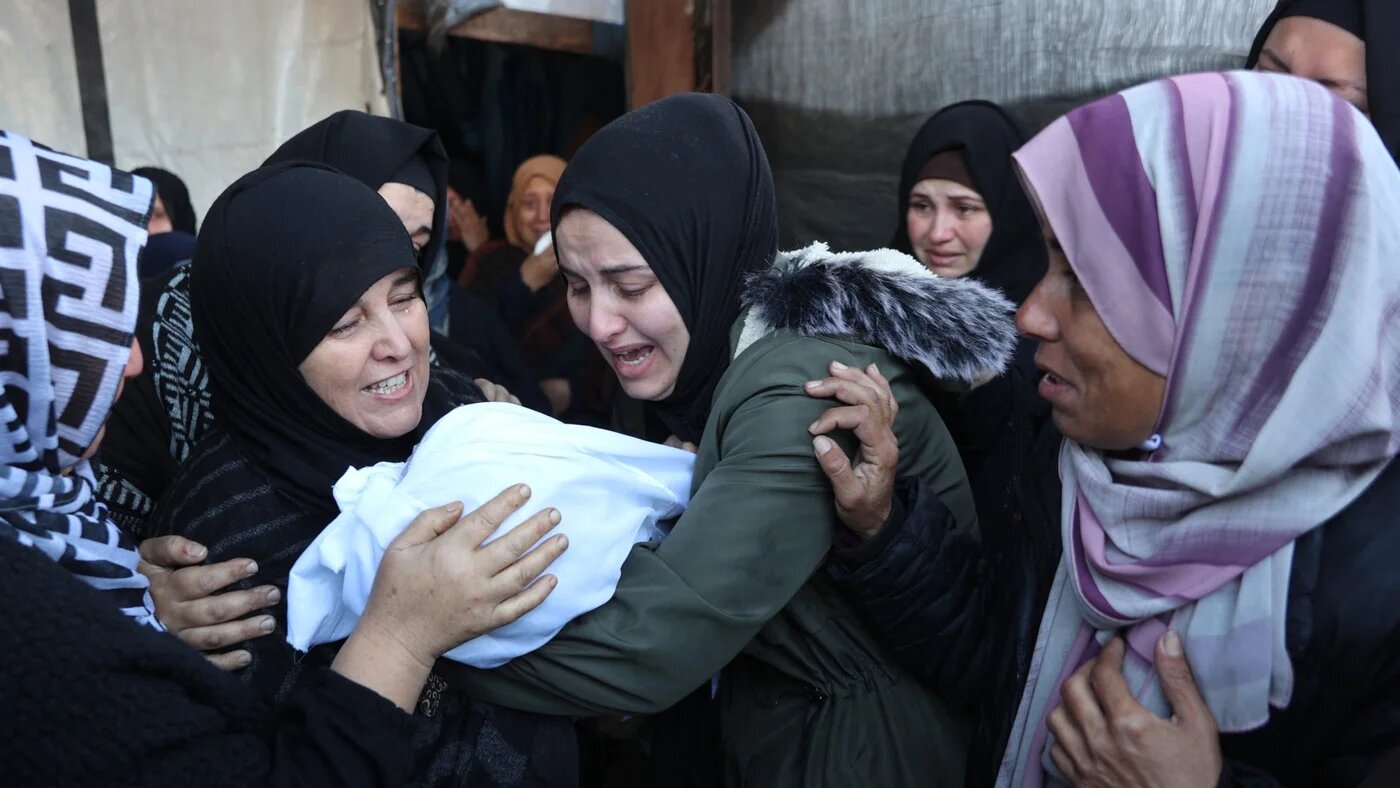 Palestinian women mourn a dead child, killed in an Israeli strike the previous night, at Al-Ahli Arab hospital, also known as the Baptist hospital, in Gaza City on 21 December 2024 (AFP/Omar Al-Qattaa)