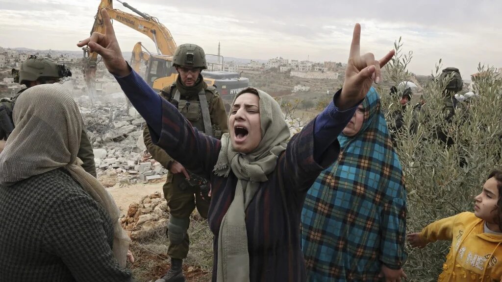 Des Palestiniennes s’insurgent contre la démolition, par l’armée israélienne, de leur maison dans la Zone C, en Cisjordanie occupée, à Hébron, le 28 décembre 2021 (AFP/Hazem Bader)