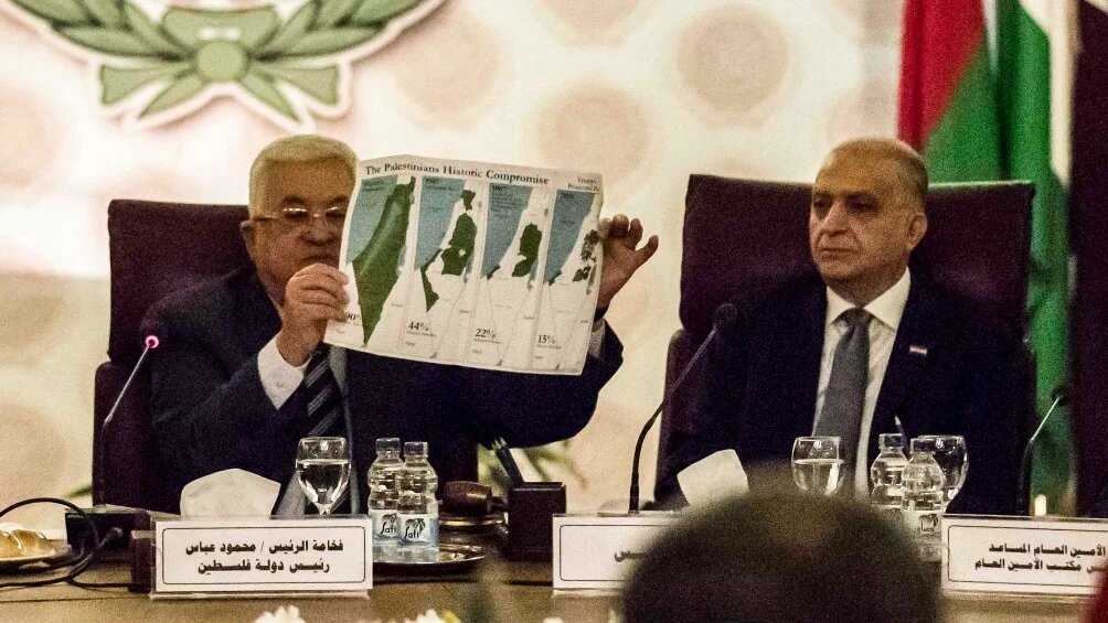 Palestinian president Mahmud Abbas (L) holds a placard of maps showing the loss over time of Palestinian territory as he attends an Arab League emergency meeting in Cairo on 1 February 2020.