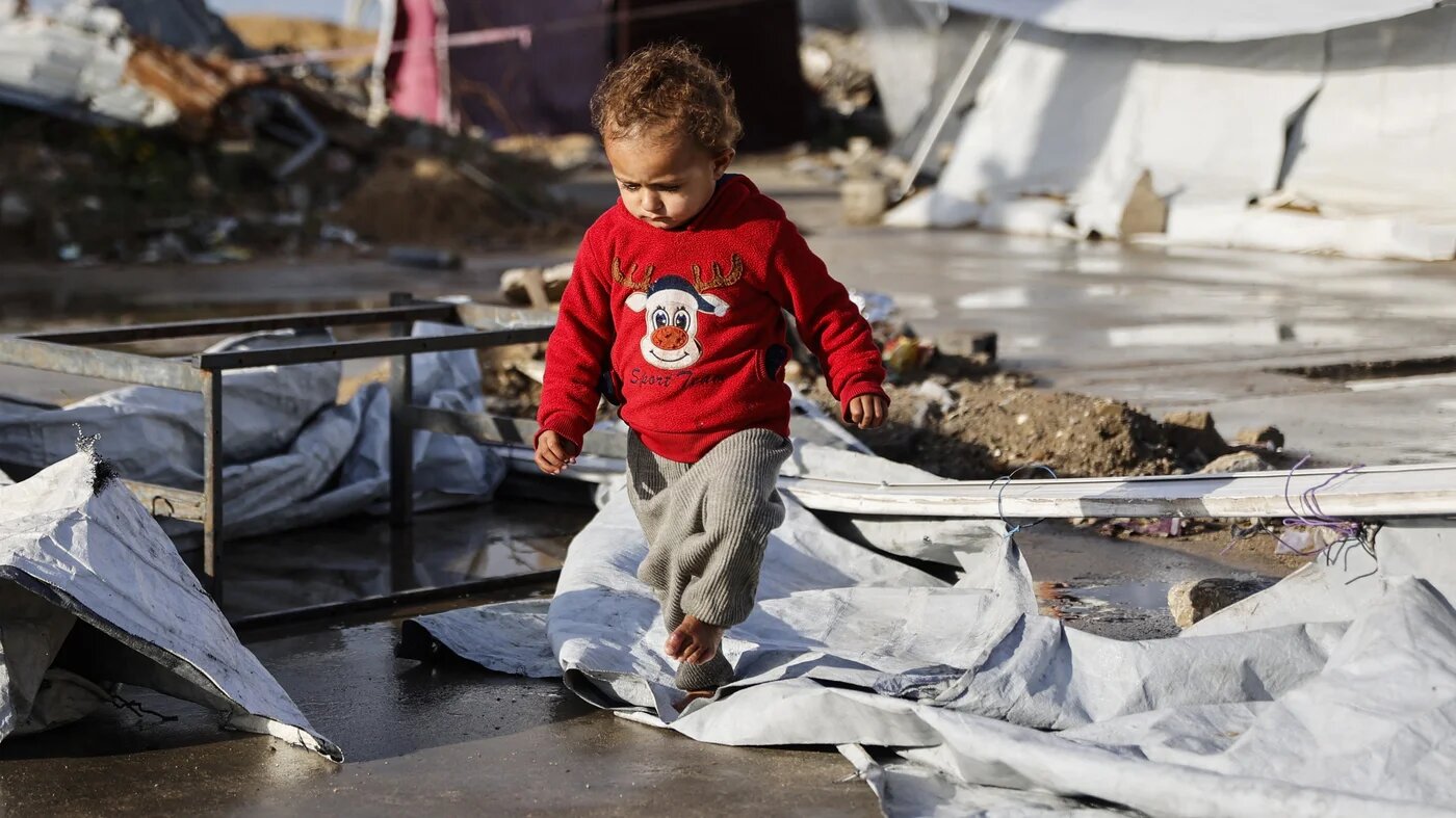 A displaced Palestinian toddler walks during winter in Gaza City, 28 December 2025 (Omar al-Qattaa/AFP)